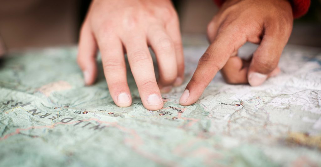 fingers pointing to a location on a map