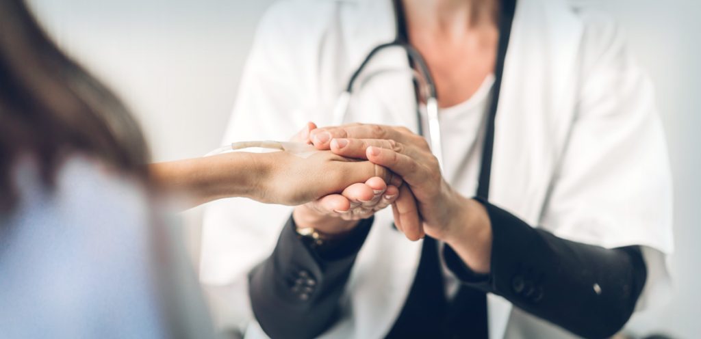 healthcare provider holding the hand of her patient